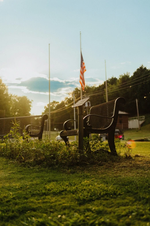 a bench and an american flag near some trees