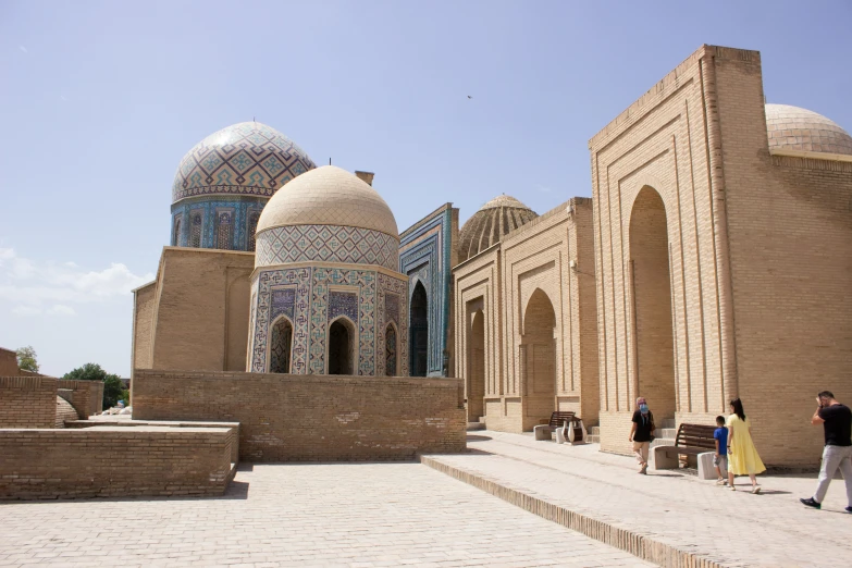 people standing in a courtyard with two stone buildings