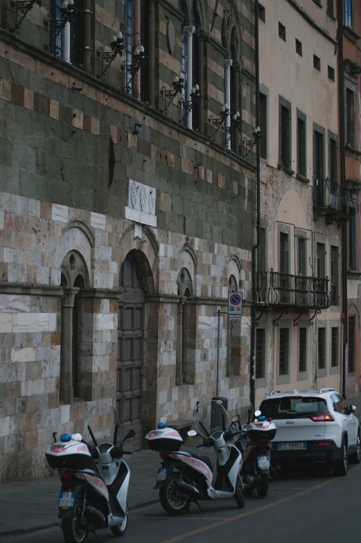 police cars and scooters parked on the side of the road near two old buildings