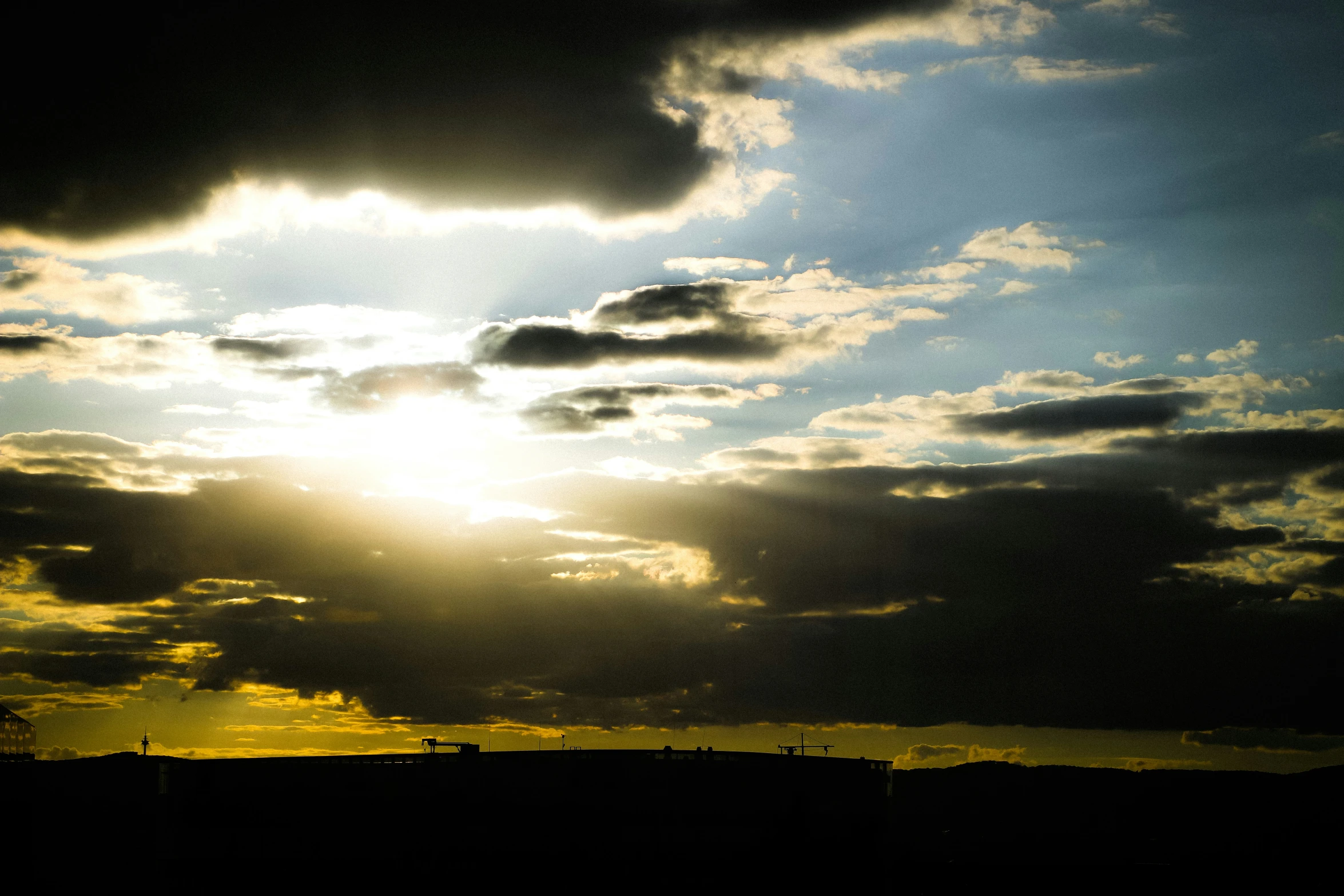 the sun peeking through the clouds above a city