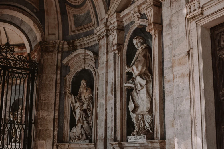 two statue's in a building next to wrought iron gates