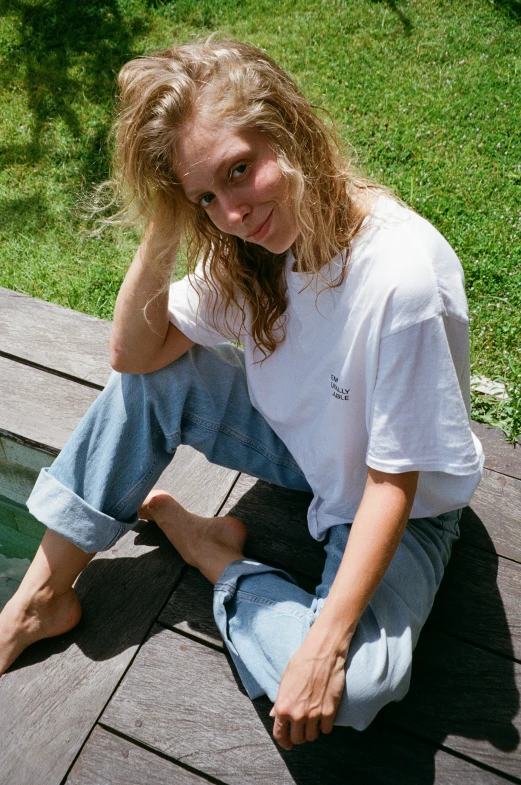 a woman sits on a porch by a swimming pool