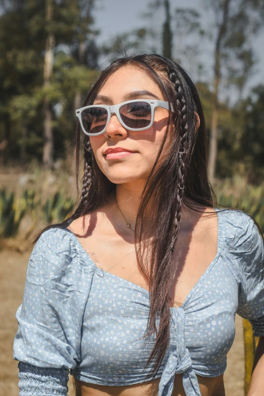 a woman wearing sunglasses stands with her hair blowing in the wind