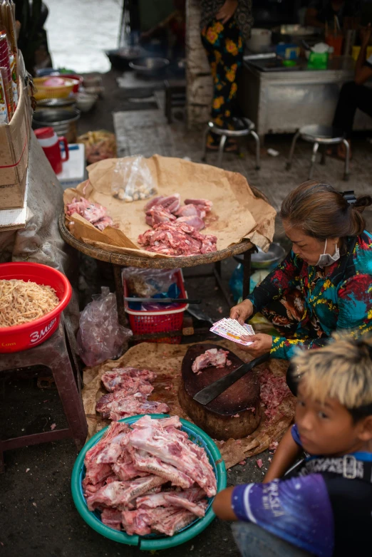 an asian lady is cooking meat and other food