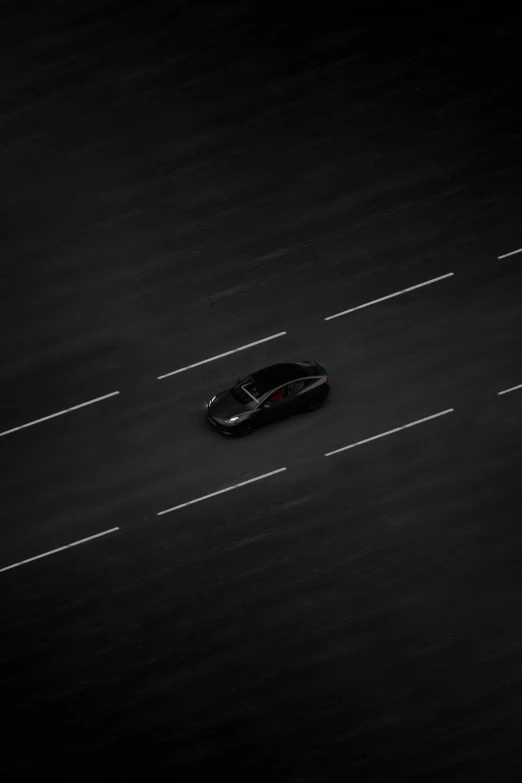 a black car driving down the middle of a highway