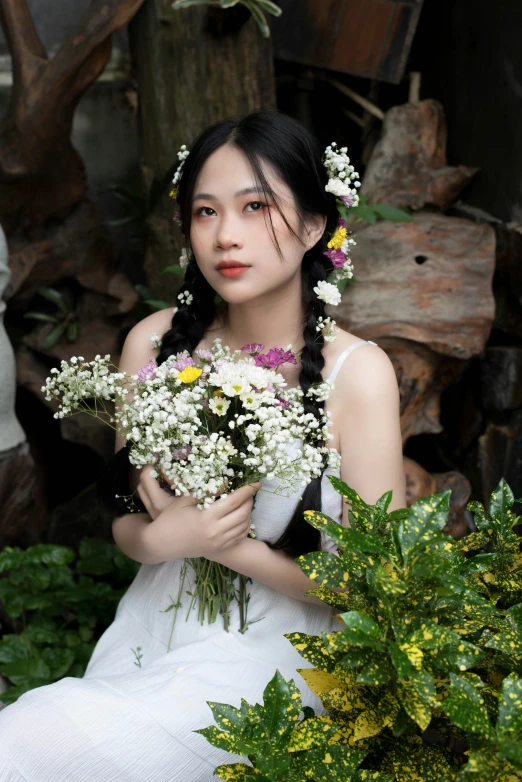 a young woman holding flowers sitting in a garden