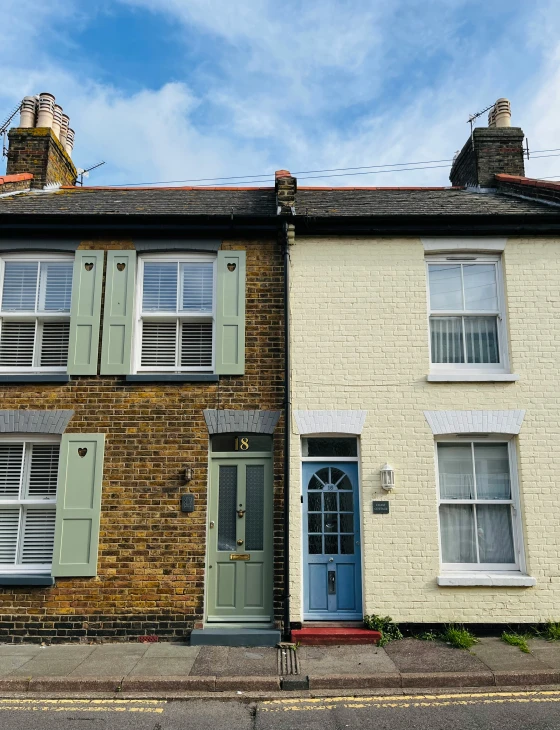 two brick buildings with green shutters on the front and blue doors