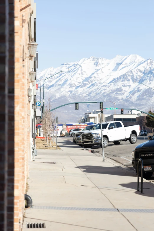 a street with several cars parked at a stoplight and a mountain in the distance