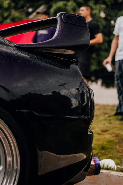 a black car with its door open and two men in the background