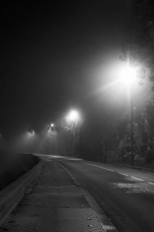 a dark night has two lamps illuminating a street