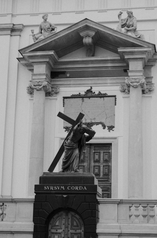 a large statue on top of a stone cross on a building