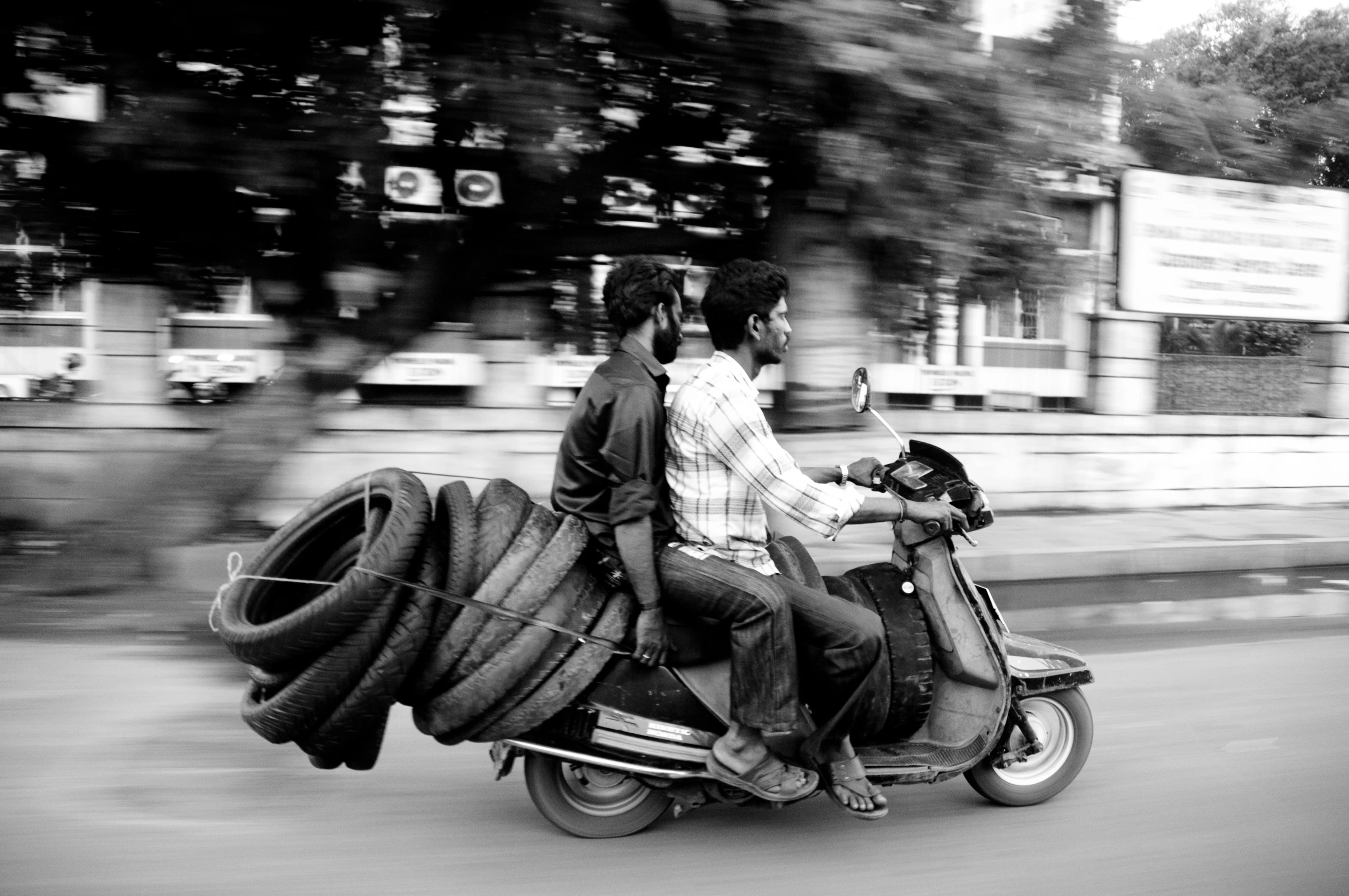 two people riding on the back of a motorcycle with huge tires