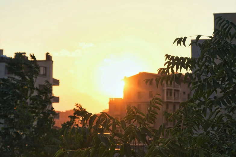 a setting sun behind some buildings with buildings