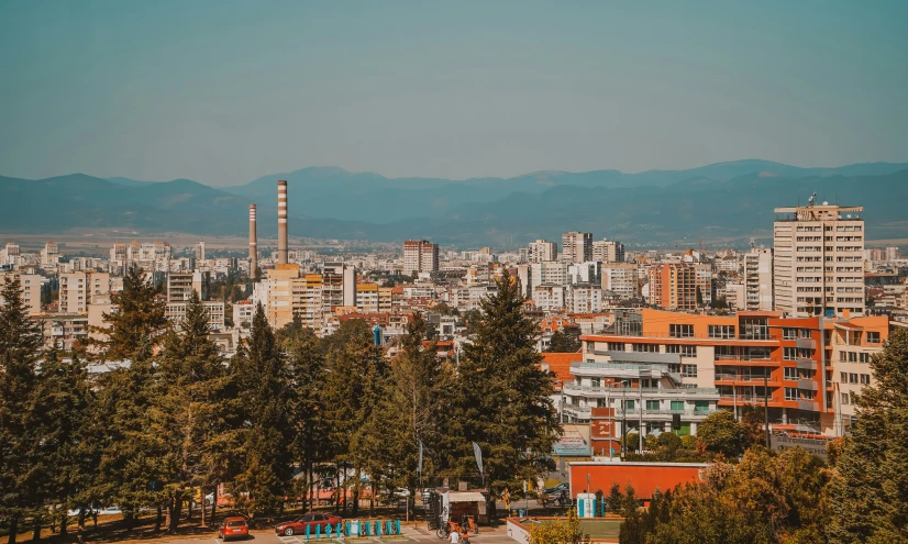 a large city with high rise buildings, mountains and trees