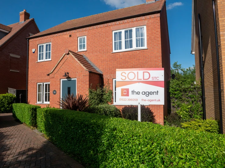 a sold out red brick home sits in the middle of some shrubbery