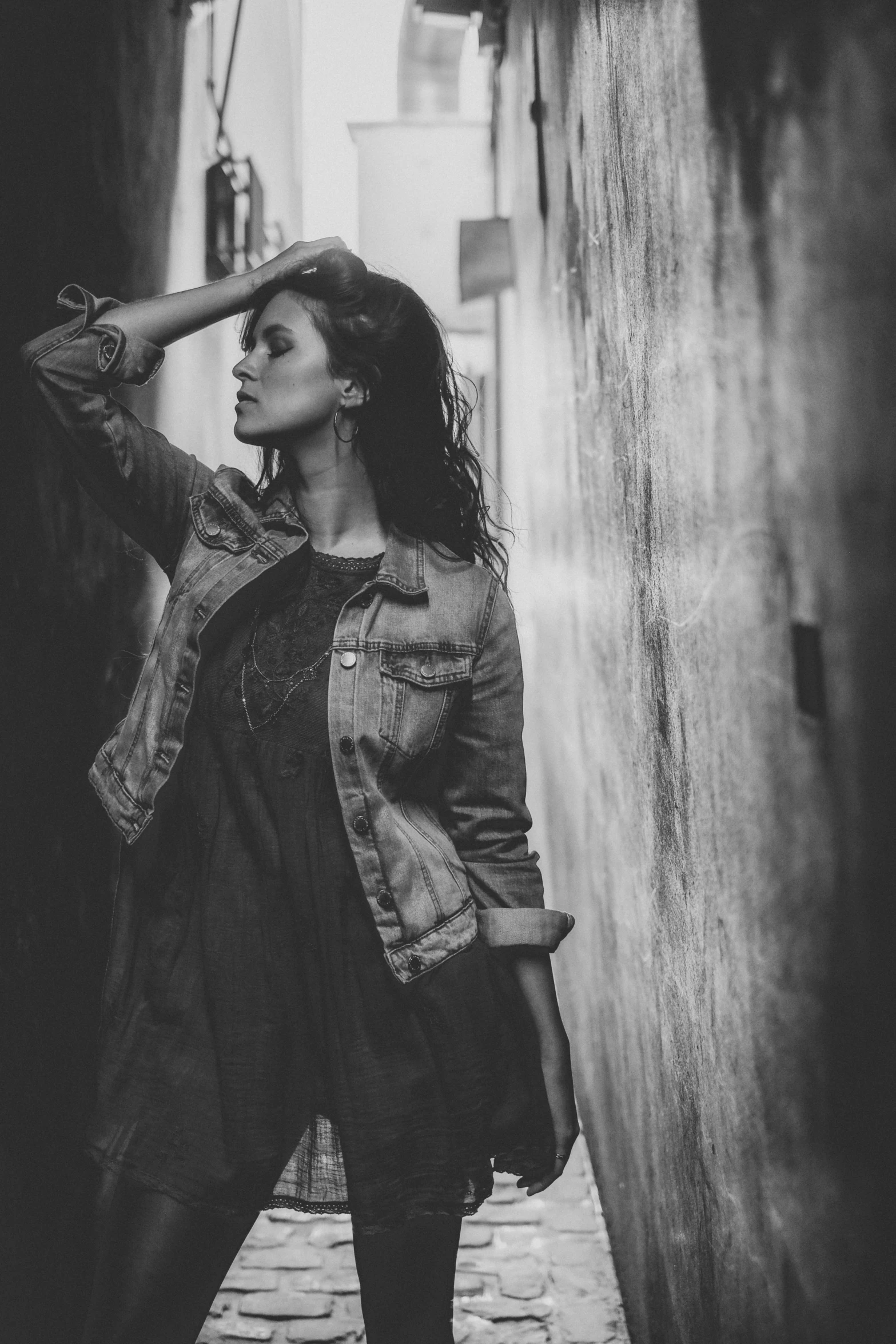 woman in denim jacket walks through a narrow street