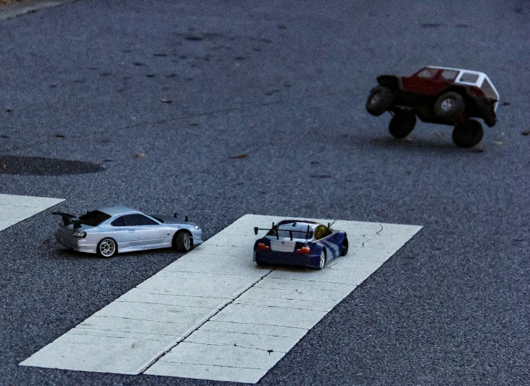 two toy cars and a truck on the street