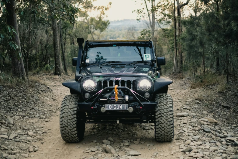 a jeep driving in the woods with a bumper guard on