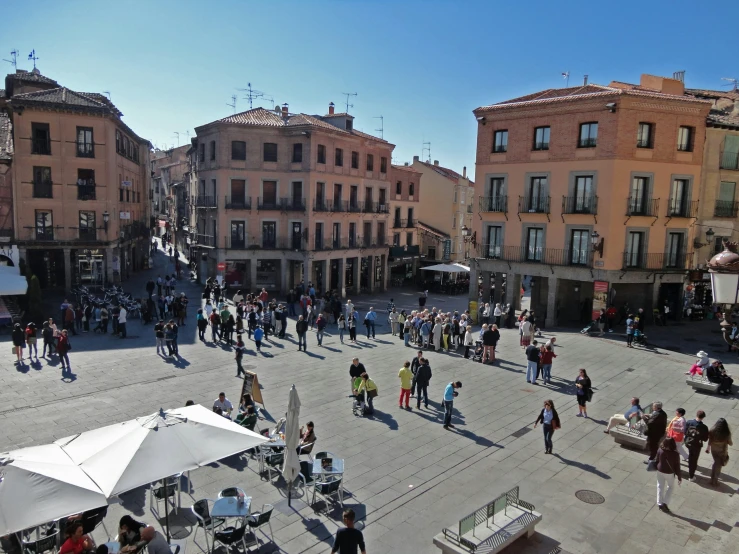 several people gather and mingle in an open courtyard with buildings