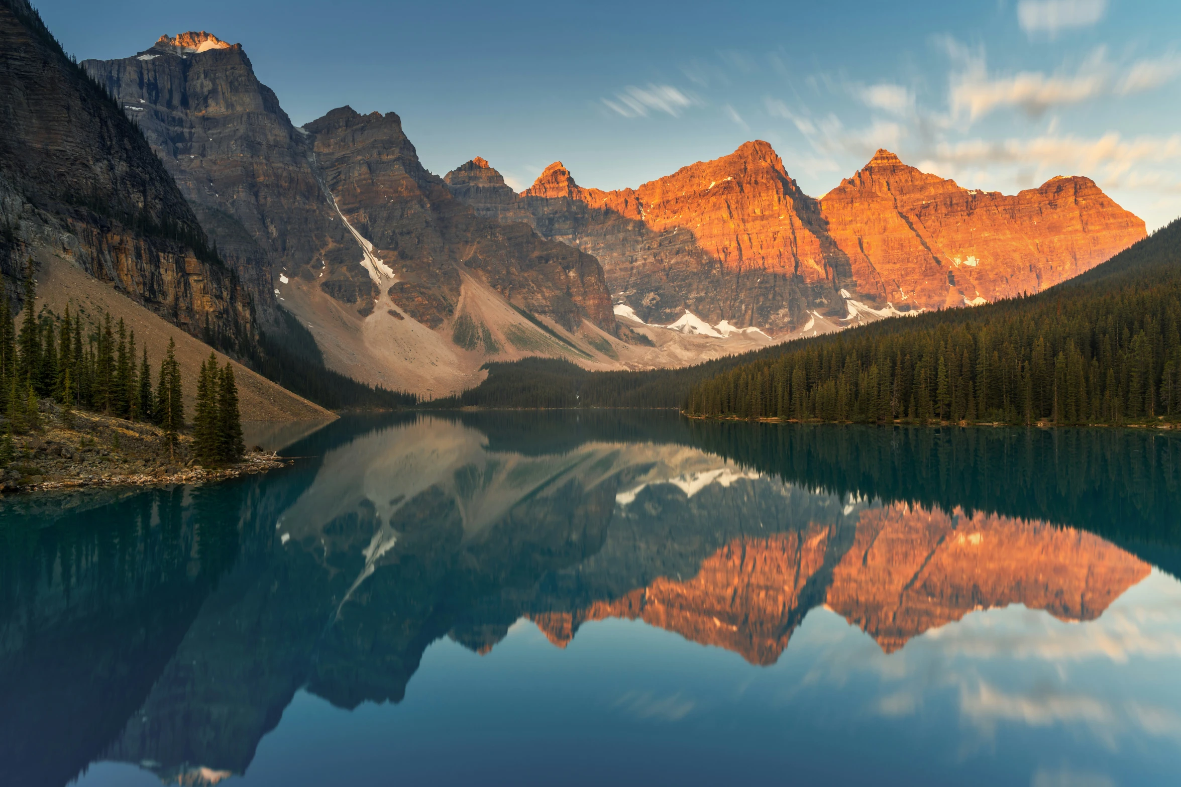 the reflection of mountain peaks in water with forest on the side