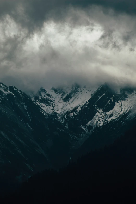 the snow capped mountains are covered in clouds