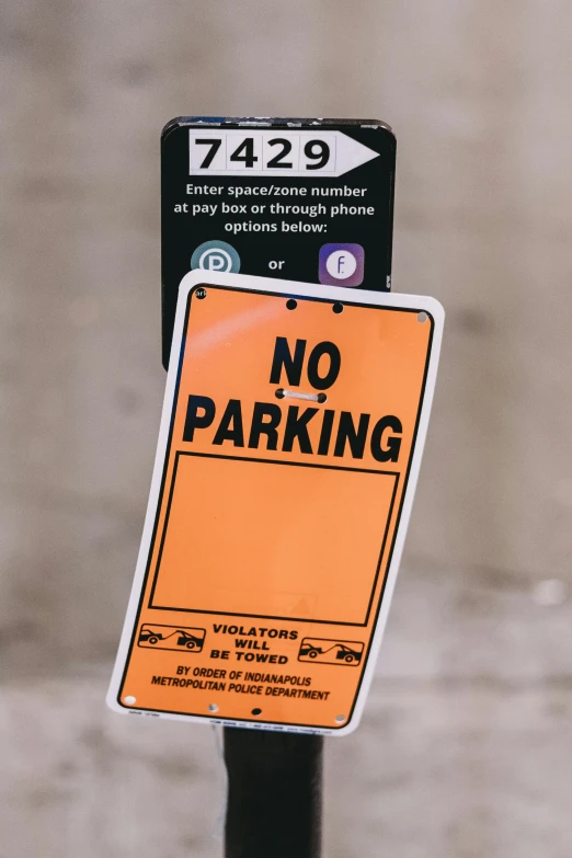 a yellow no parking sign sitting on the side of a street