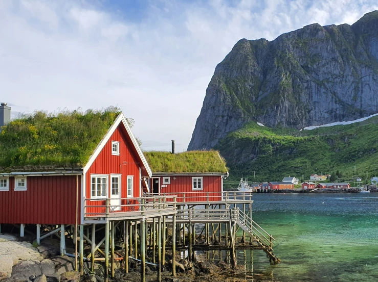 a pier next to houses on stilts that have a grass roof