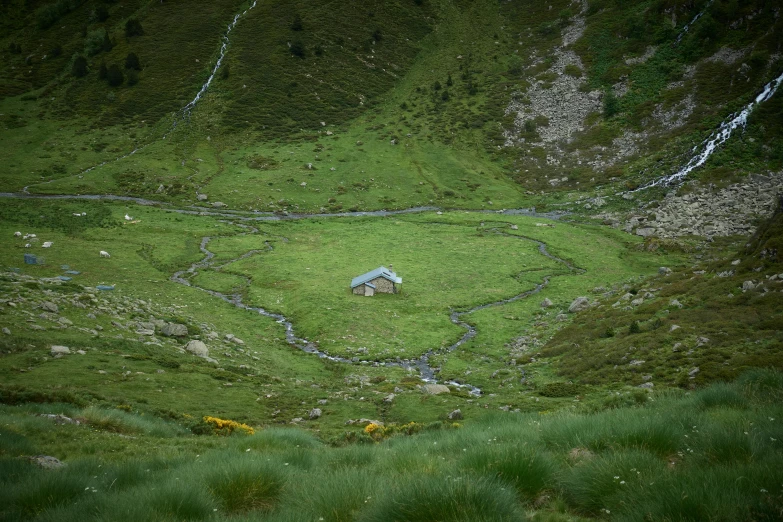 a green pasture that has a house sitting in the middle