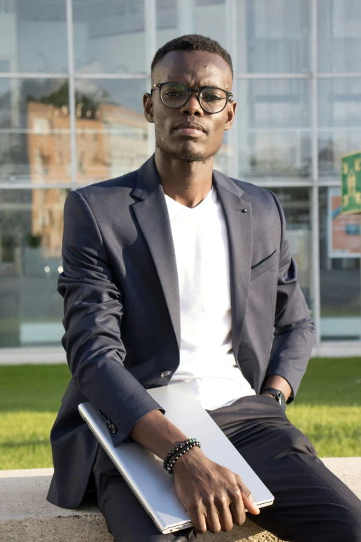 an african american man sitting outside holding a laptop