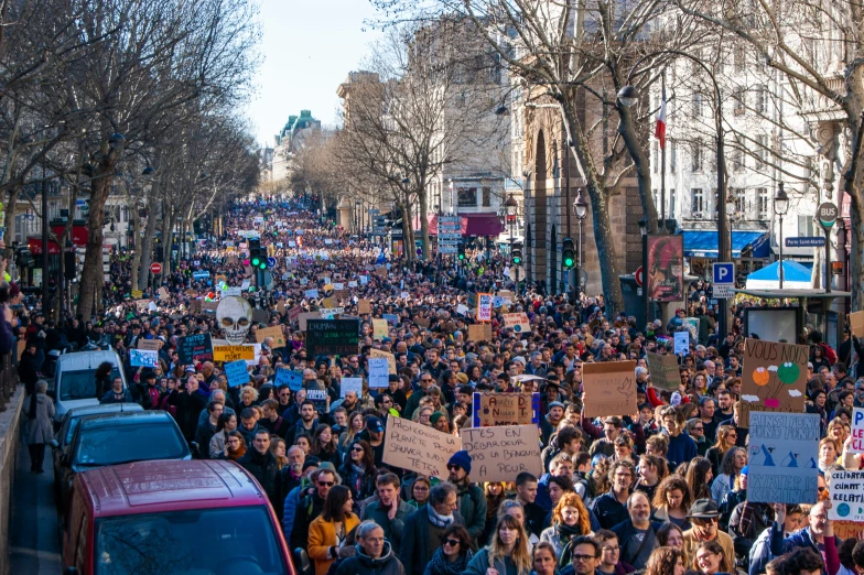 several people walking down a city street as people hold up signs