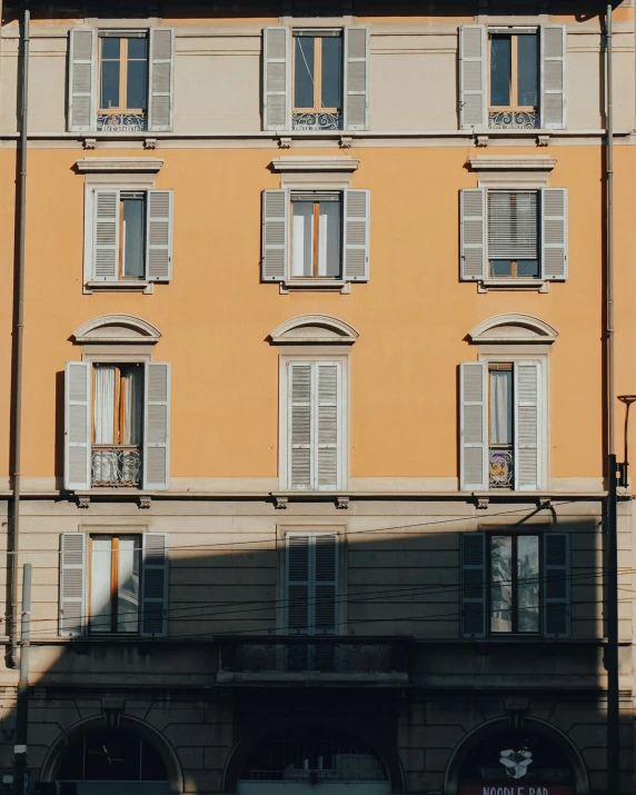 a yellow building with lots of windows has a traffic light and sign on the front