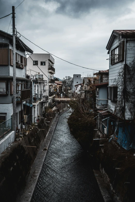 a waterway runs between two buildings, under a gray sky