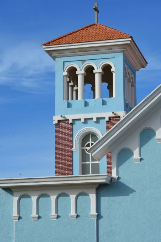 a steeple on a blue and white building has a cross at the top