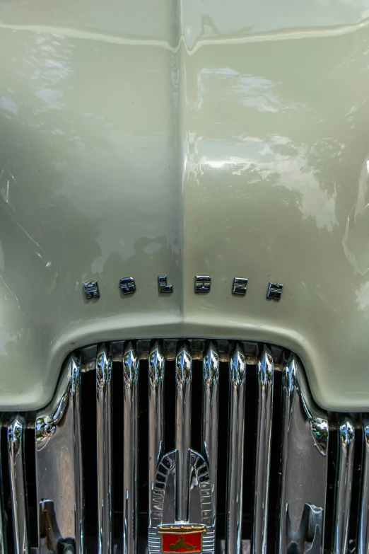 a white classic car front grill has two chrome and black rivets