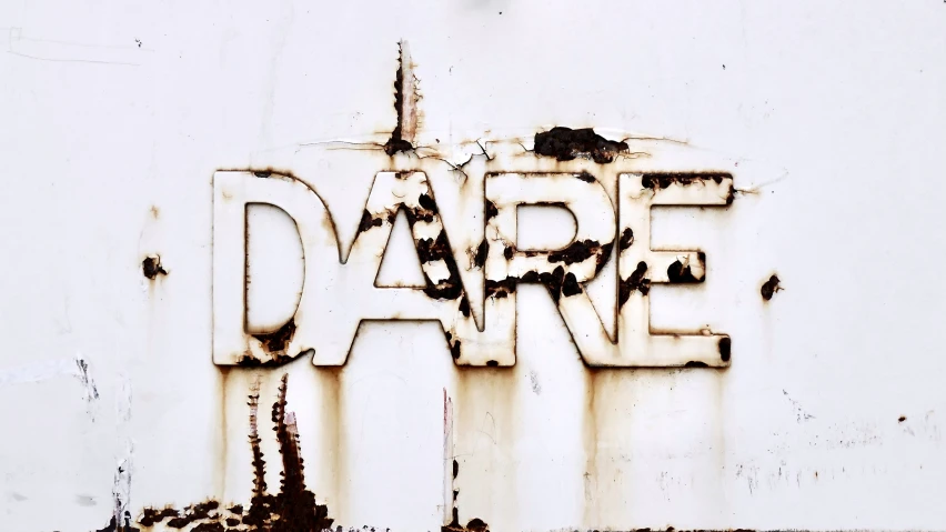 a rusty sign written in a font that says dare