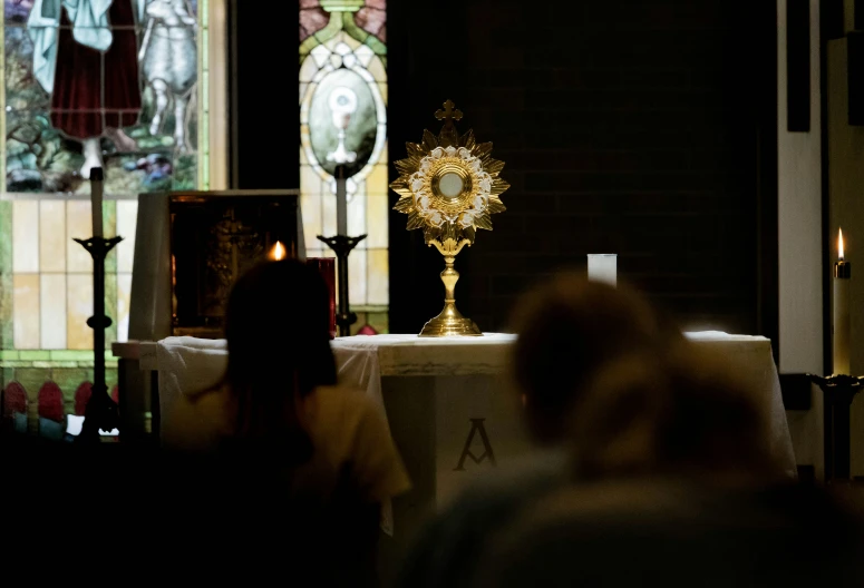 people stand in front of a cross with a golden cross on it