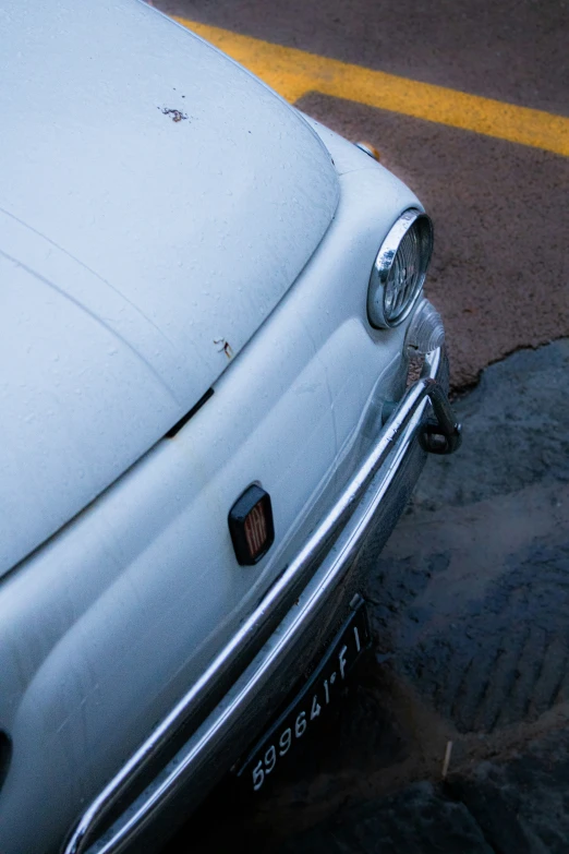 the front of an old white car parked in a parking lot