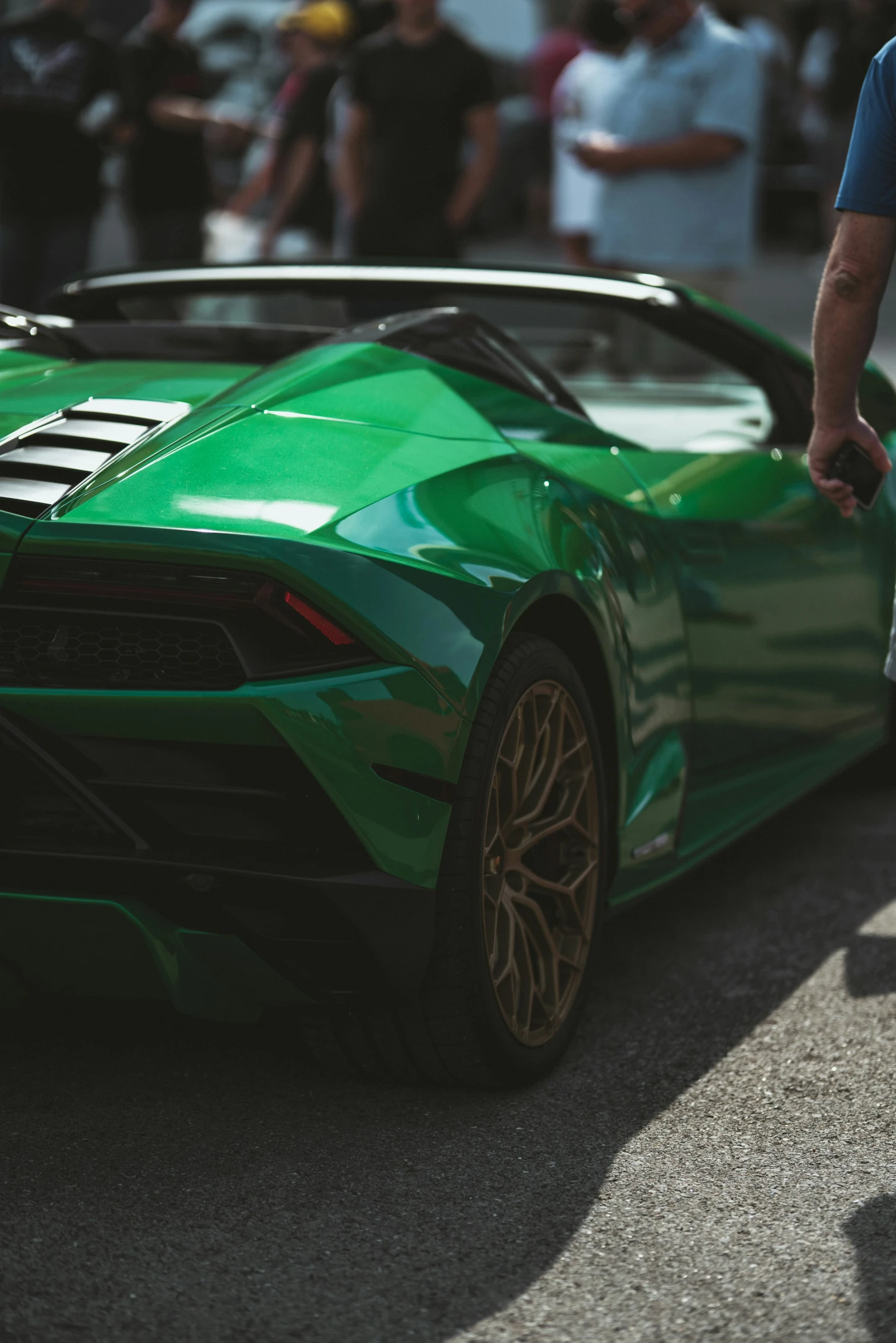 a green sports car parked in front of an open crowd