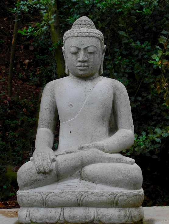 a statue sitting in a position on some cement