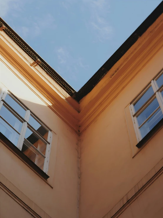 two windows against an orange building, the sky is mostly blue