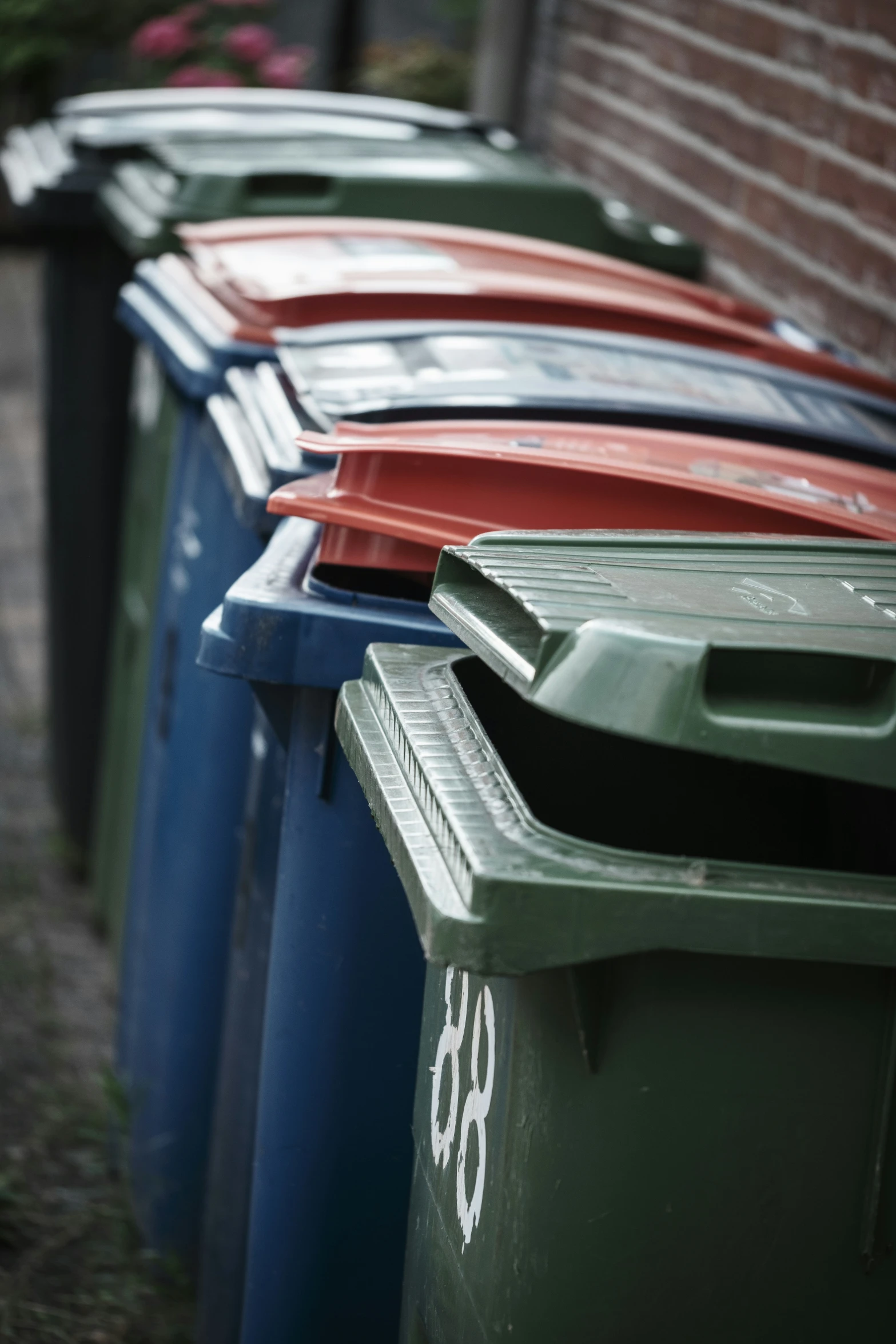 a row of brightly colored trash cans sitting next to a brick wall