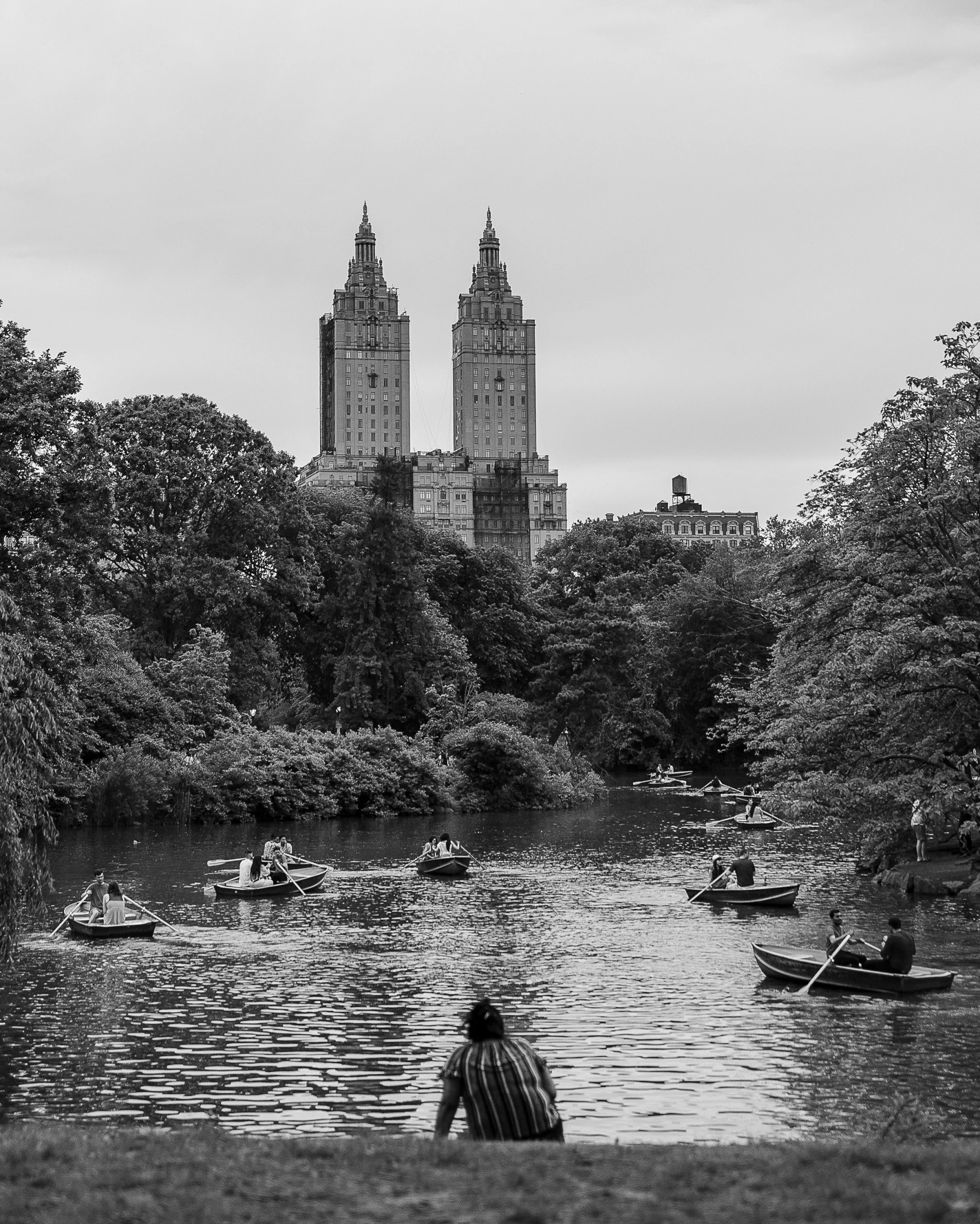 a lake with many boats and large buildings in the distance