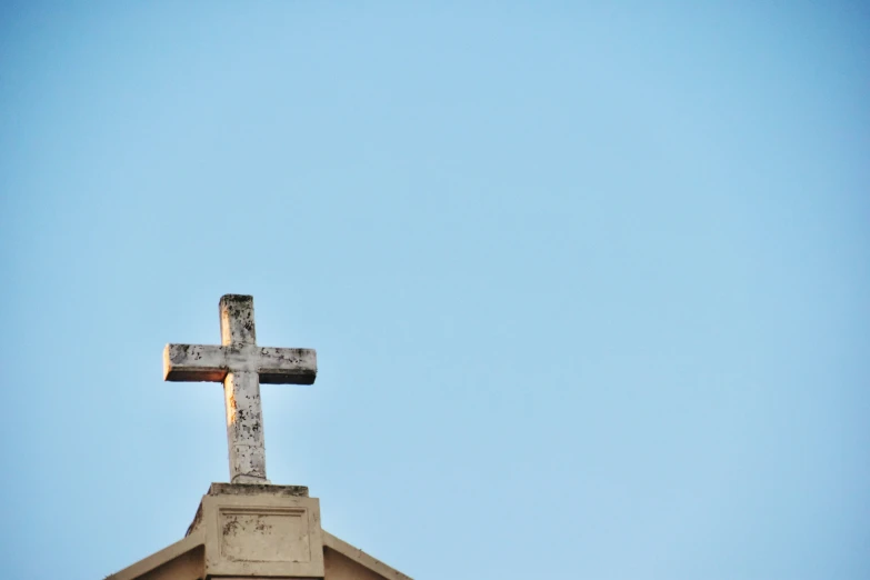 a cross atop a building in the middle of the day