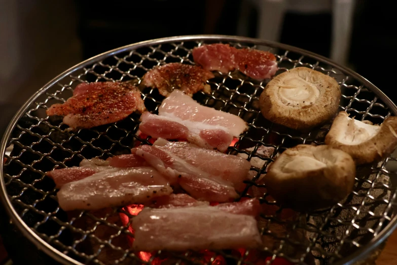 meat and mushrooms are cooking in a large grill