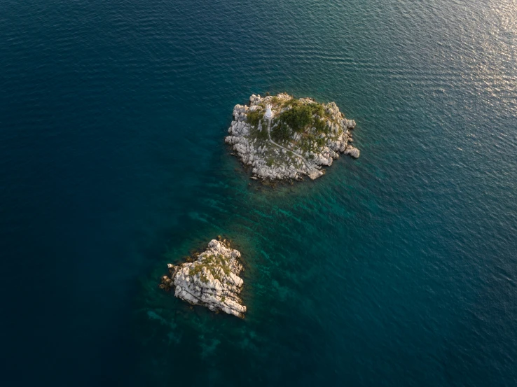 a view of two small, rocky islands in the water