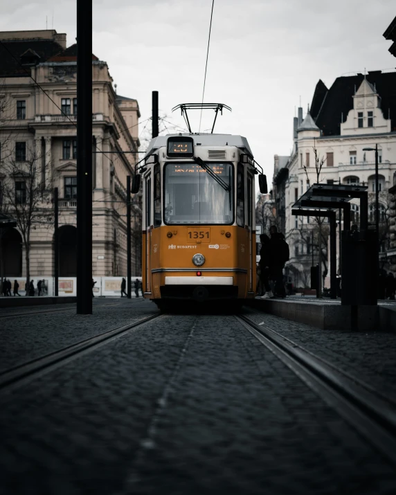 a yellow train traveling down tracks near many buildings