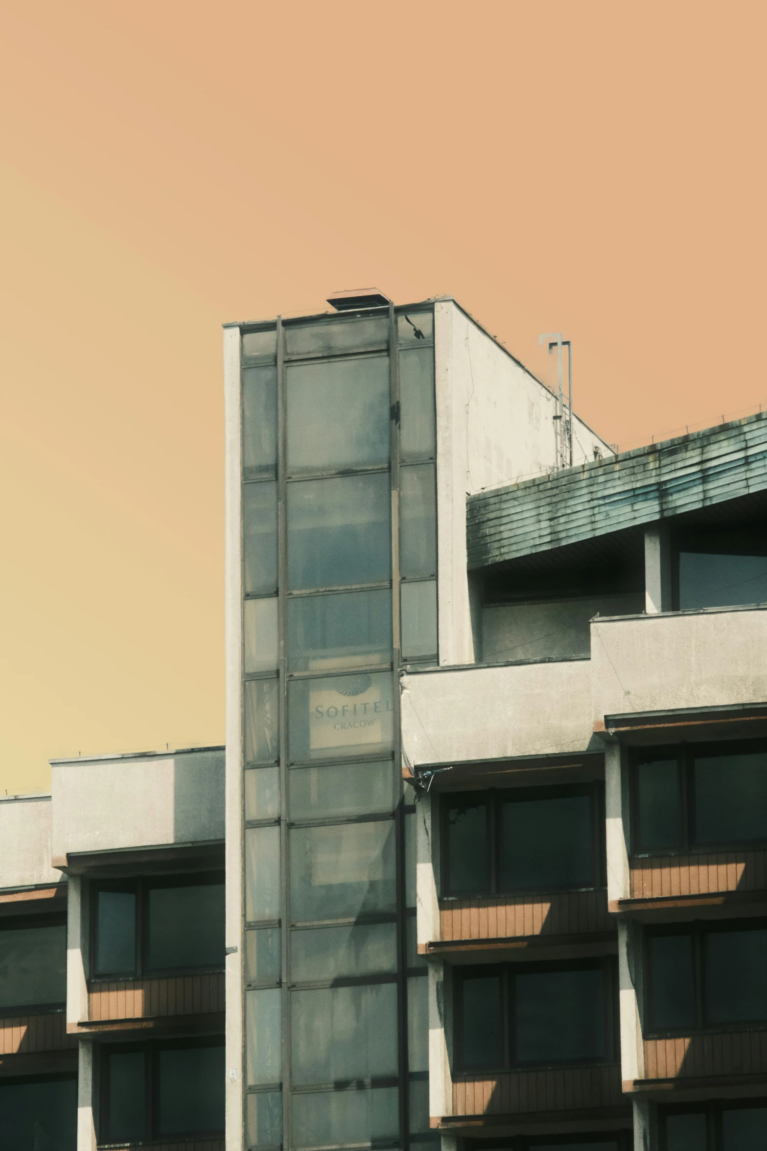 there is a building with windows, a rooftop, and a red airplane flying in the sky