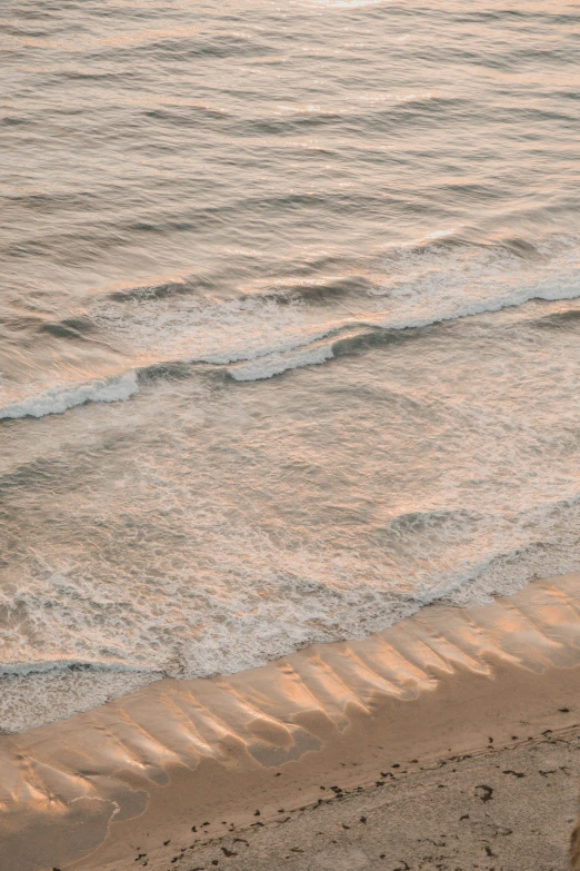 a person standing on the beach next to the water with a surfboard