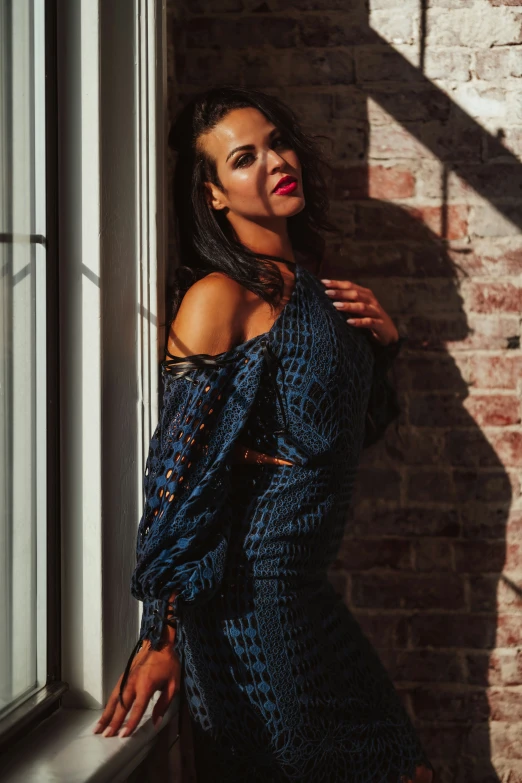 a woman is standing against a window in front of a brick building