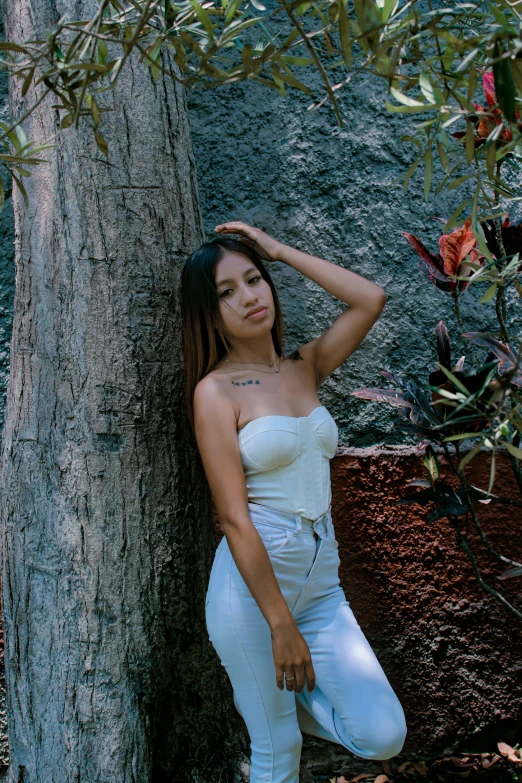 young asian model poses in white tights next to tree